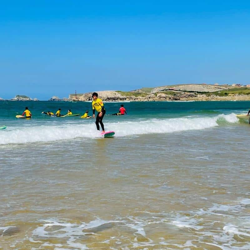 niño surfeando sobre una tabla amarilla en la actividad del multiaventura cantabria de surf