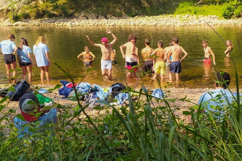 grupo de adolescentes en la orilla de un lago durante su campamento multiaventura