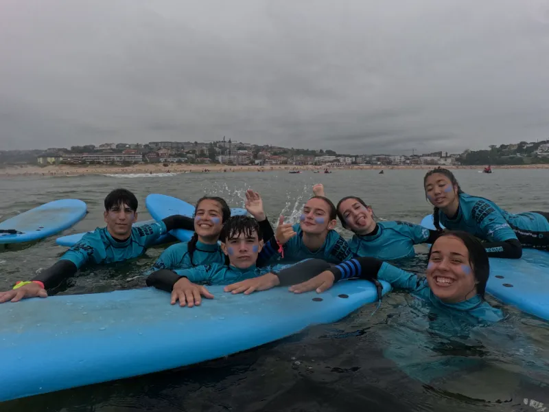 Adolescentes en el mar con tablas de surf